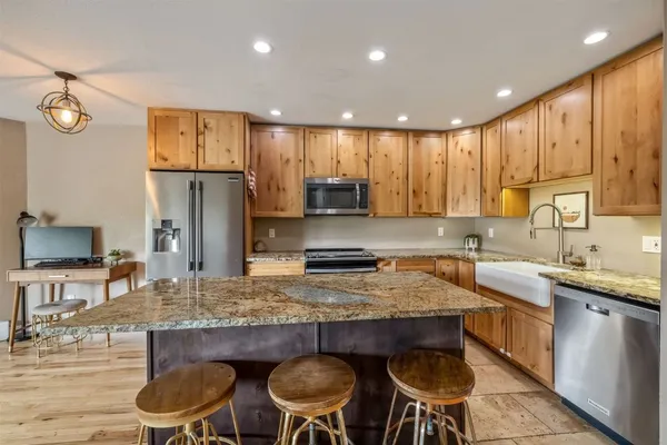 a kitchen with granite countertop a table chairs stove refrigerator and cabinets