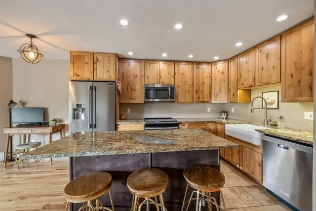 a kitchen with granite countertop a table chairs stove refrigerator and cabinets