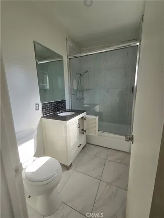 a white toilet sitting next to a bathroom sink and a shower