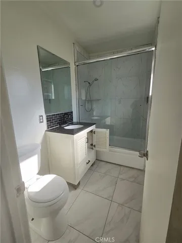a white toilet sitting next to a bathroom sink and a shower