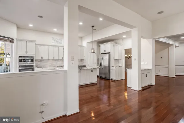 a kitchen with stainless steel appliances kitchen island granite countertop a stove a sink and white cabinets with wooden floors