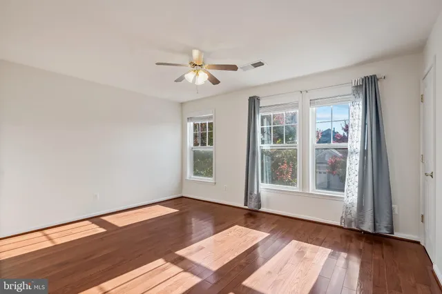 a view of an empty room with window and wooden floor