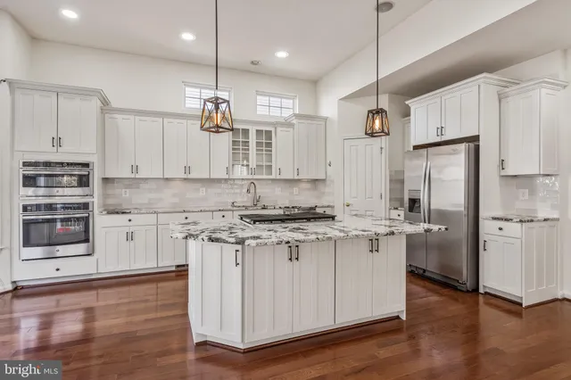 a kitchen with kitchen island white cabinets and stainless steel appliances