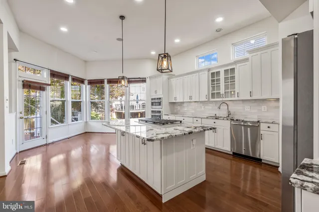 a kitchen with kitchen island granite countertop wooden floors and white cabinets