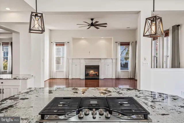 a kitchen with kitchen island granite countertop a stove a sink a center island with wooden floor and chandelier