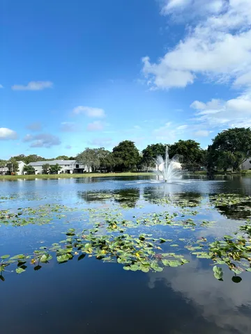 a view of a lake with a yard and large trees