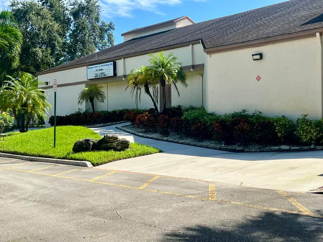 a view of a house with a yard and palm trees