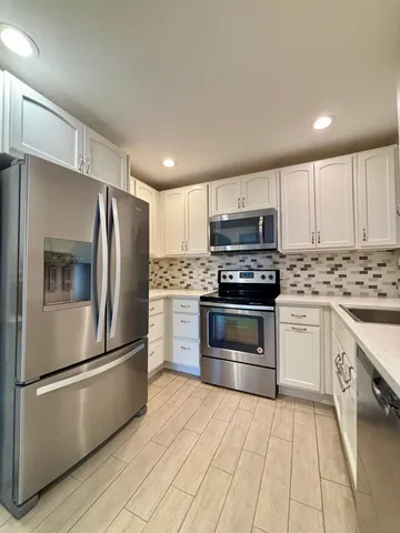 a kitchen with granite countertop a refrigerator and a stove top oven