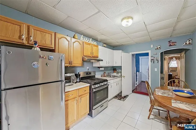 a kitchen with stainless steel appliances granite countertop a refrigerator a stove a sink dishwasher and white cabinets with wooden floor