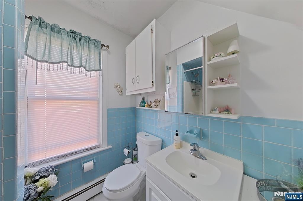 42 Grand Street Garfield, NJ 07026 - Photo 22 of 26 a bathroom with a sink a toilet and shower curtain