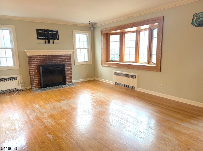 34 Howard Street Verona, NJ 07044 - Photo 6 of 20 a view of an empty room with wooden floor fireplace and a window