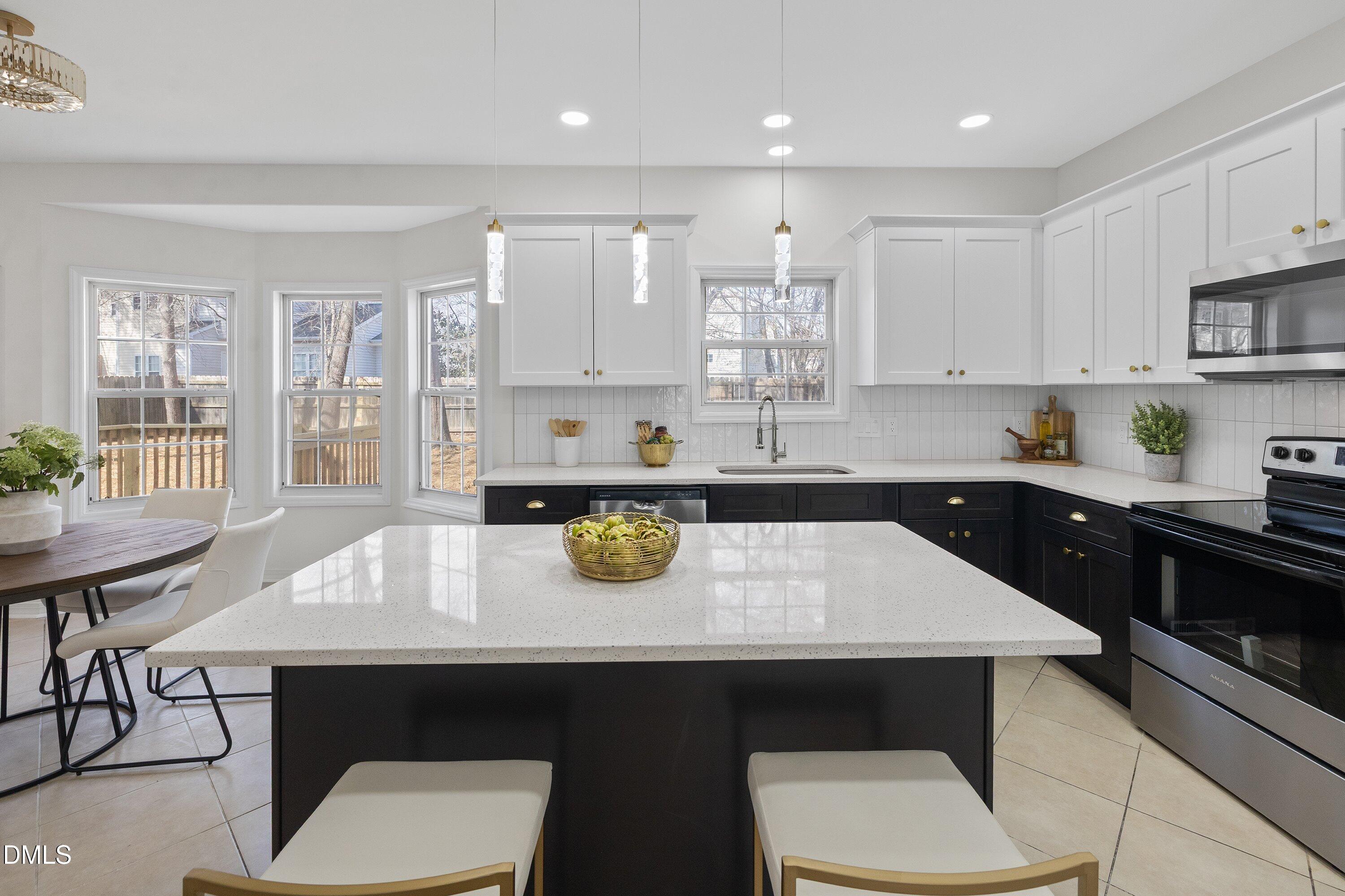 a kitchen with kitchen island a sink dishwasher a stove a dining table and chairs