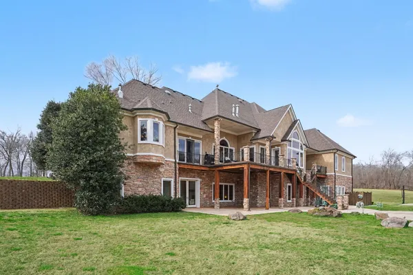 a view of a house with a big yard and large trees