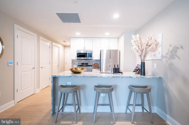 a kitchen with stainless steel appliances a table and chairs in it