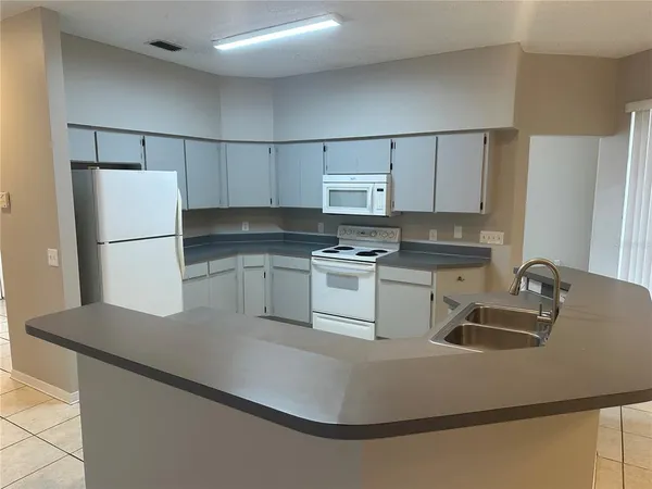 a kitchen with kitchen island a sink a refrigerator and white cabinets