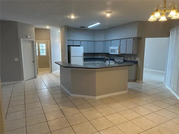 an open kitchen with kitchen island granite countertop a refrigerator and a stove top oven