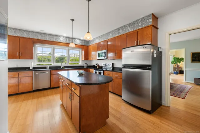 a kitchen with stainless steel appliances granite countertop a refrigerator a sink a stove a washer dryer and a refrigerator