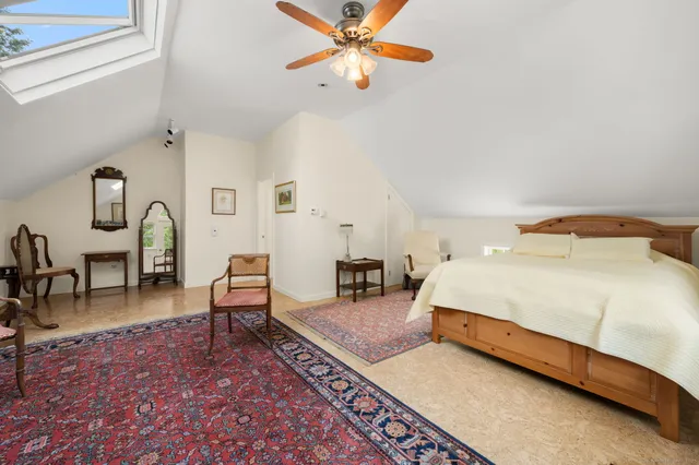 a spacious bedroom with a bed a chandelier and a rug