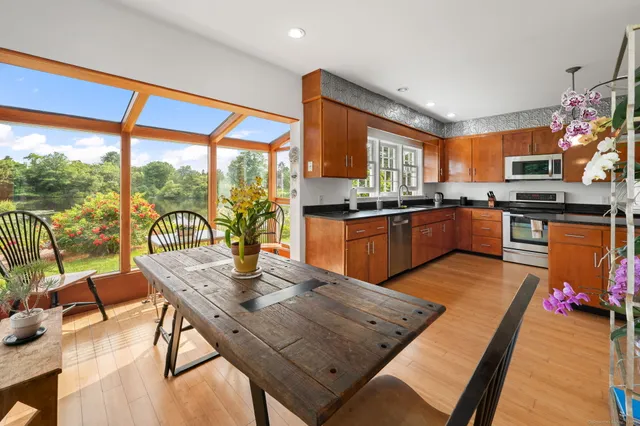 a view of a kitchen with kitchen island granite countertop a stove a sink a dining table and chairs with wooden floor