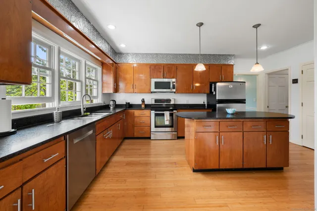 a large kitchen with stainless steel appliances granite countertop a stove a sink and a granite counter tops