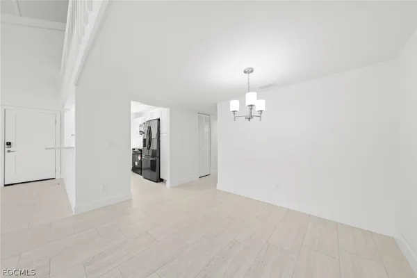 an empty room with chandelier fan and windows
