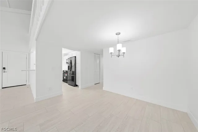 an empty room with chandelier fan and windows