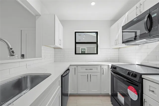 a kitchen with white cabinets a sink dishwasher and a stove with wooden floor