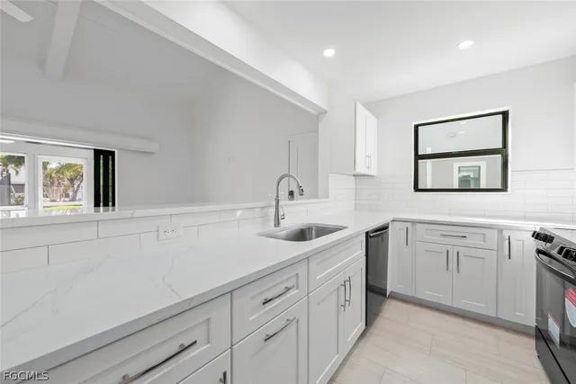 a kitchen with white cabinets and sink