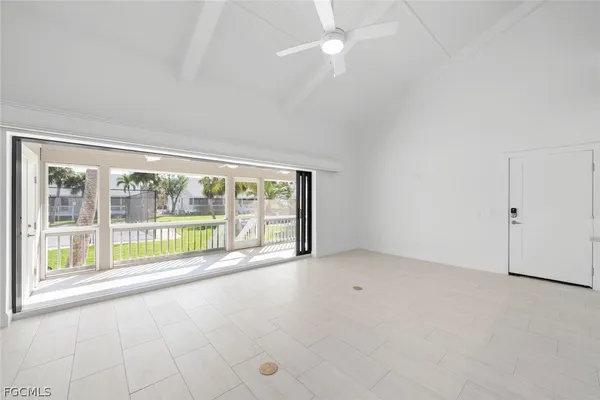 an empty room with chandelier fan and windows