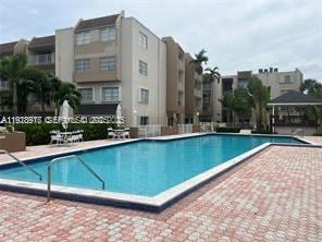 7747 Southwest 86th Street, Unit D411 Miami, FL 33143 - Photo 14 of 17 a view of a swimming pool with outdoor seating and plants