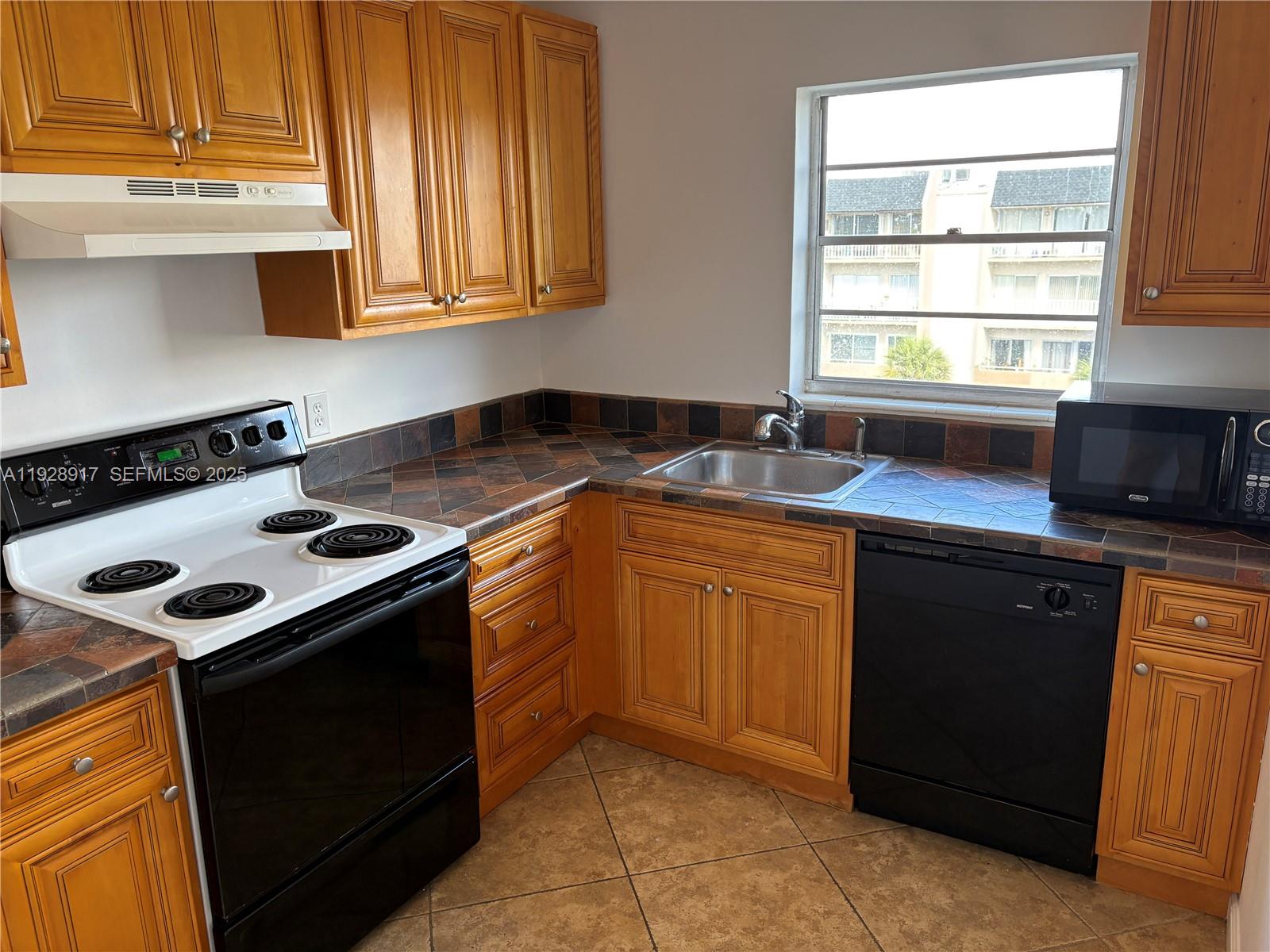 7747 Southwest 86th Street, Unit D411 Miami, FL 33143 - Photo 6 of 17 a kitchen with a sink stove top oven and cabinets