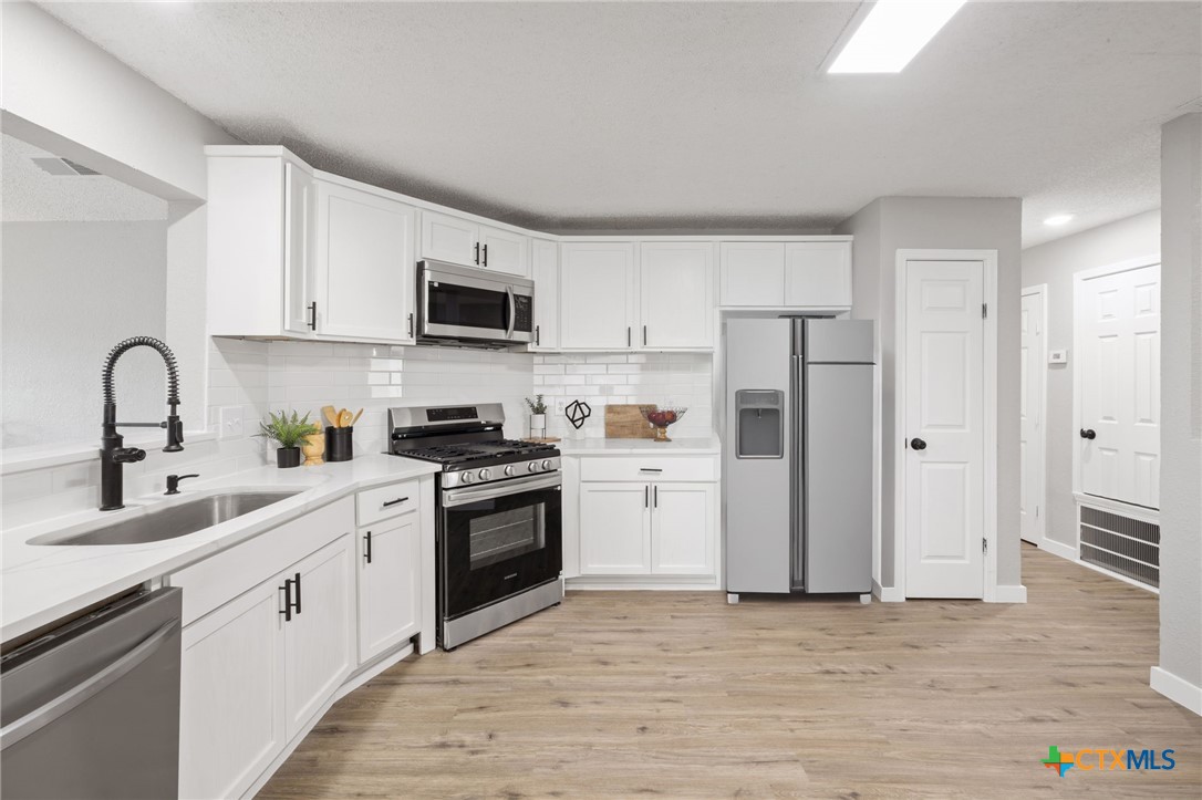 804 Antelope Trail Temple, TX 76504 - Photo 14 of 32 a kitchen with white cabinets and stainless steel appliances