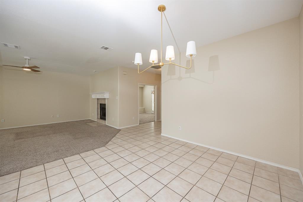 1828 Mercer Way Savannah, TX 76227 - Photo 18 of 38 Spare room featuring ceiling fan, a chandelier, light tile patterned floors, a tile fireplace, and light colored carpet
