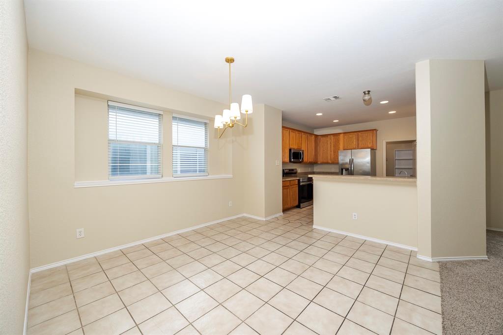 1828 Mercer Way Savannah, TX 76227 - Photo 8 of 38 Kitchen featuring brown cabinets, a chandelier, appliances with stainless steel finishes, light tile patterned floors, and recessed lighting