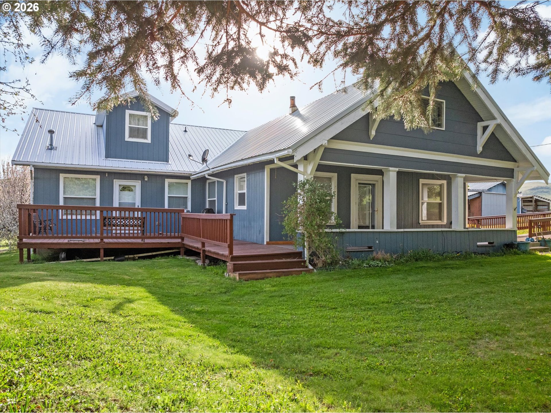 a view of a house with a yard deck and a large tree