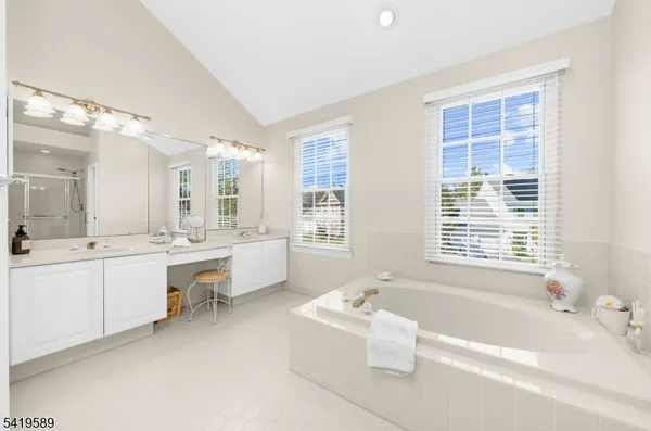 a bathroom with a tub a double vanity sink a large mirror and a bathtub next to a window