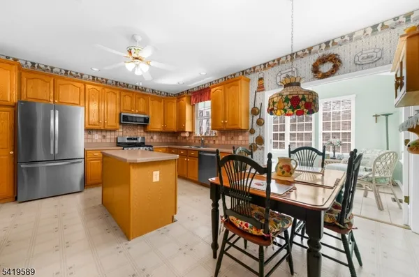 a kitchen with stainless steel appliances kitchen island granite countertop a refrigerator a stove a sink a dining table and chairs with wooden floor
