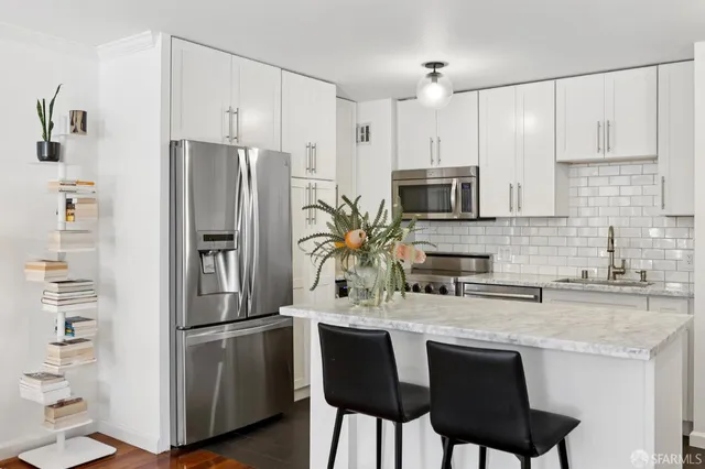 a kitchen with refrigerator a sink and chairs