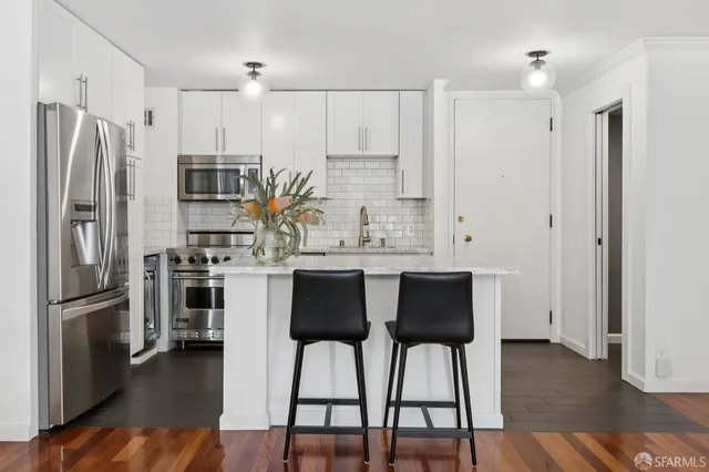 a kitchen with stainless steel appliances a refrigerator a stove microwave and a dining table