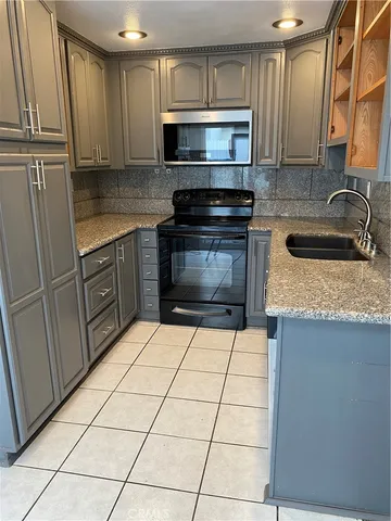 a kitchen with granite countertop a sink a stove top oven and cabinets
