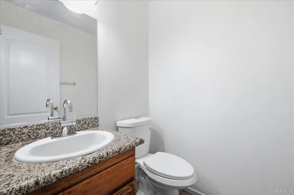 a bathroom with a granite countertop toilet a sink and a mirror