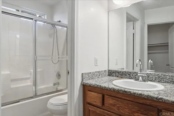 a bathroom with a granite countertop sink toilet and shower