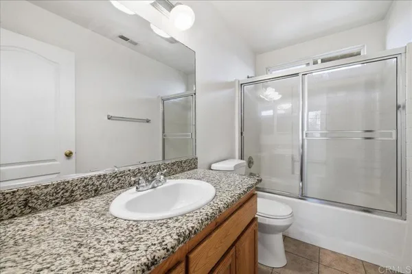 a bathroom with a granite countertop sink toilet a mirror and shower