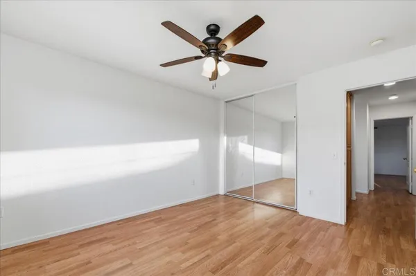 an empty room with wooden floor and ceiling fan