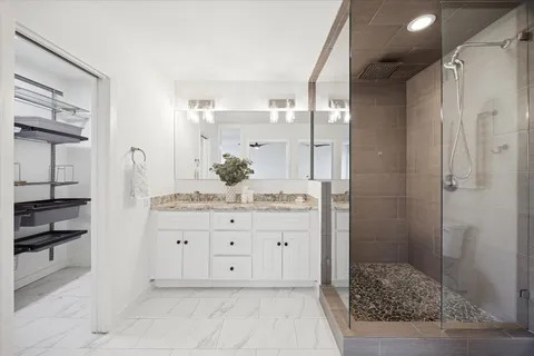 a bathroom with a granite countertop sink a mirror and shower