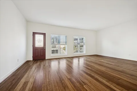 an empty room with wooden floor cabinet and windows