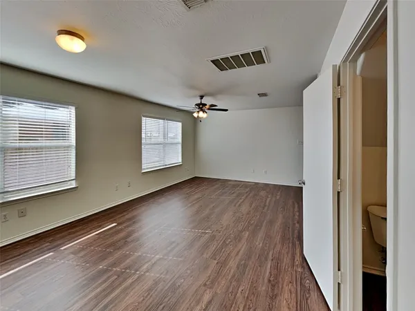 a view of empty room with wooden floor and fan