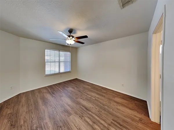 an empty room with wooden floor chandelier fan and windows