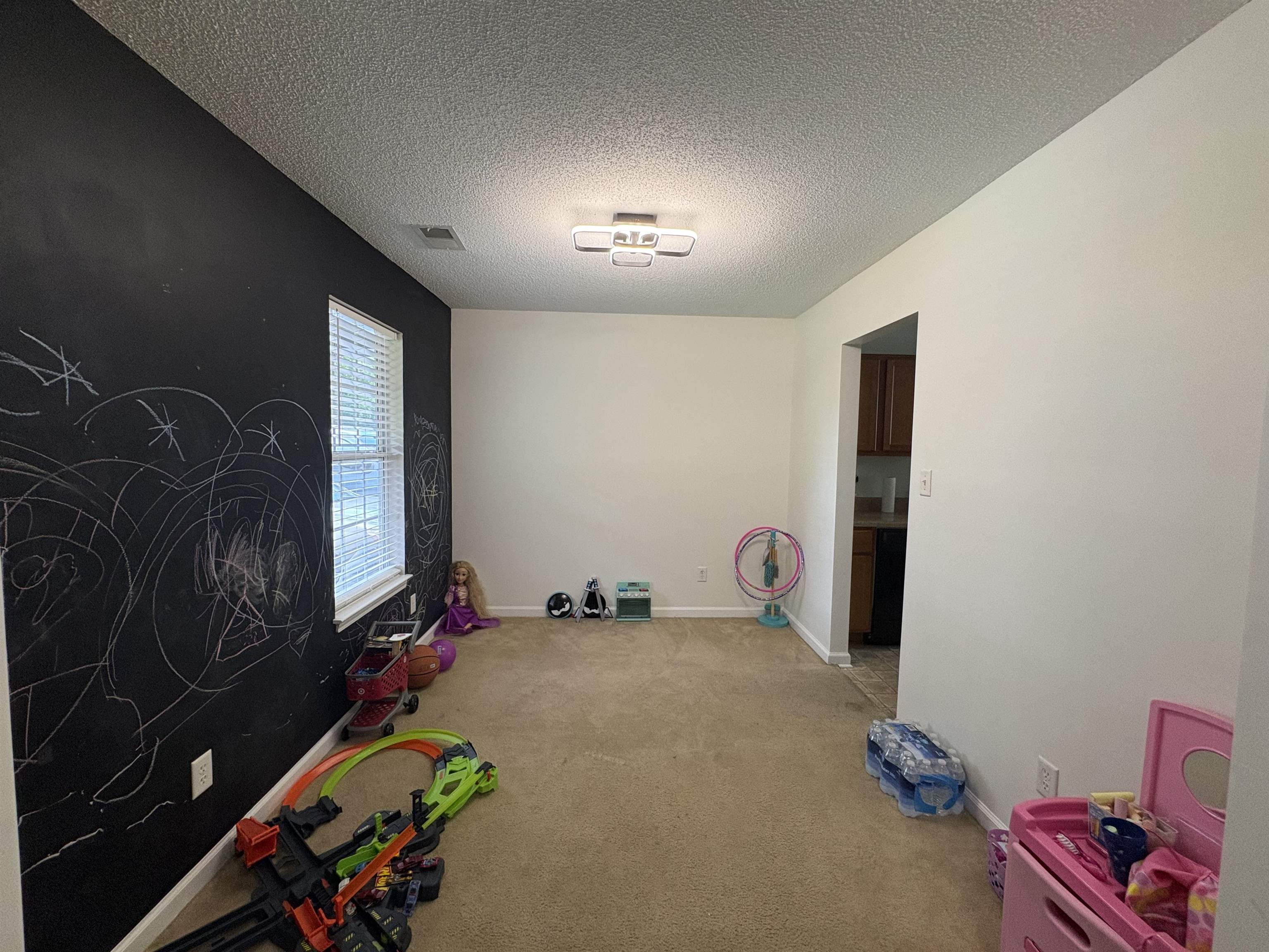 4356 Cedar Hills Road Memphis, TN 38135 - Photo 5 of 29 Spacious room with a chalkboard accent wall, textured ceiling, and carpeted flooring