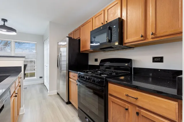 a kitchen with stainless steel appliances granite countertop a stove top oven microwave and cabinets